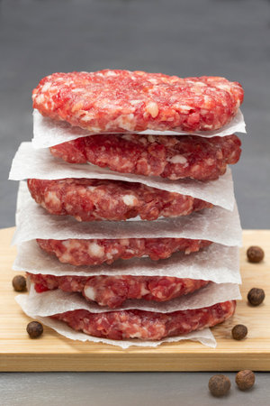 Raw beef burgers are stacked on board. close up. gray backgroundの写真素材
