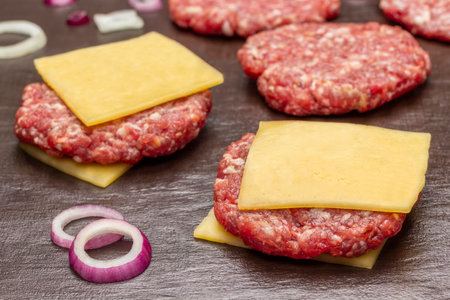 Raw beef burgers with cheese on brown background. top view. close upの写真素材