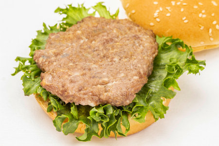 Fried burger bun on lettuce leaf. top view. white backgroundの写真素材