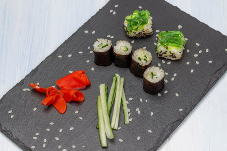 Sushi nori and sushi with seaweed, sliced cucumber and pickled ginger on stone board. top view. white background.の写真素材