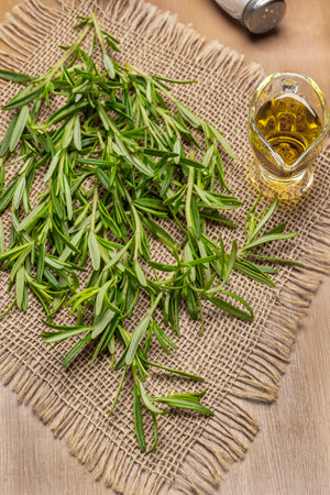 Olive oil in glass bowl and rosemary on burlap napkin. flat lay. brown backgroundの写真素材