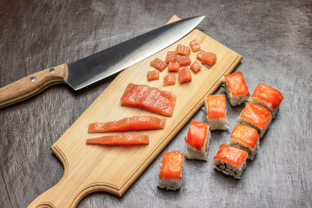 Sliced salmon and knife on cutting board. Sushi with salmon on table. top view. brown background.の写真素材