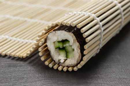 Nori sushi roll in a bamboo mat. close up. gray backgroundの写真素材