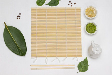 Bamboo mat, chopsticks, sushi spices and green leaves on the table. flat lay. white backgroundの写真素材