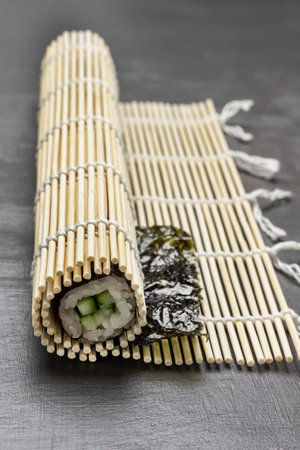 Sushi nori with cucumber on a bamboo mat. close up. gray backgroundの写真素材
