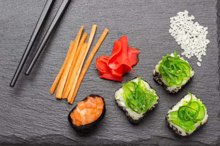 Sushi with seaweed, sliced carrots, ginger on stone board. flat layの写真素材