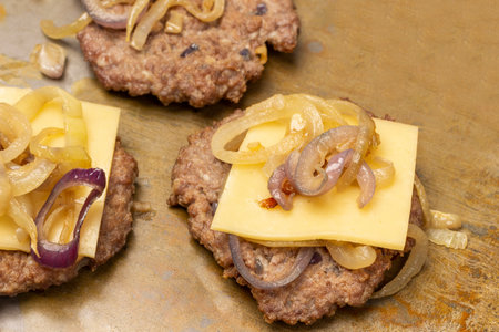 Fried burger with cheese and fried onions. Rusty background. top view.の写真素材