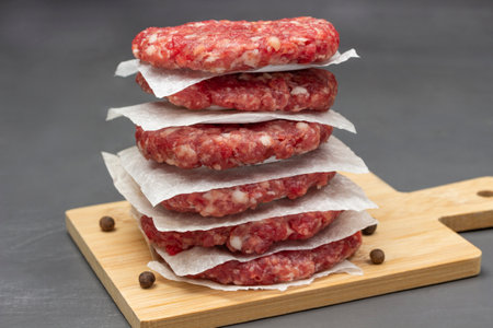 Raw beef burgers are stacked on board. close up. gray backgroundの写真素材