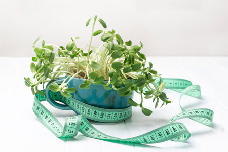 Measuring tape around blue mug with sunflower sprouts. white background. top viewの写真素材