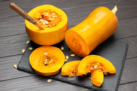 Knife in pumpkin. Pumpkin slices on stone cutting board. top view. dark wooden backgroundの写真素材