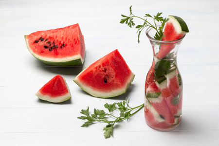 Homemade vitamin watermelon water with greens in glass jar. Piece of watermelon on table. top view. white background.の写真素材