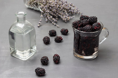Blueberry infused water in glass mug. Water bottle. Lavender on table. top view. gray background.の写真素材