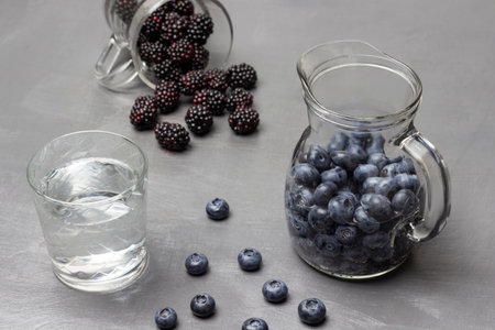 Blackberry water in glass mug. Blueberry in glass and on table. water in glass. gray background.の写真素材