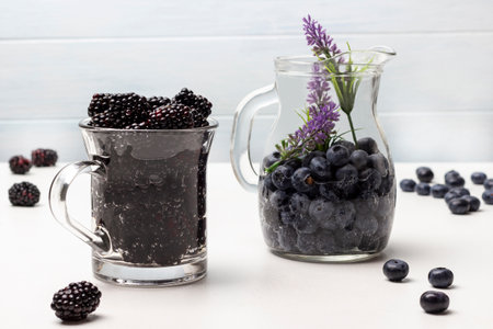 Blackberry and blueberry infused water in glass mugs. Berries on table. white background.の写真素材