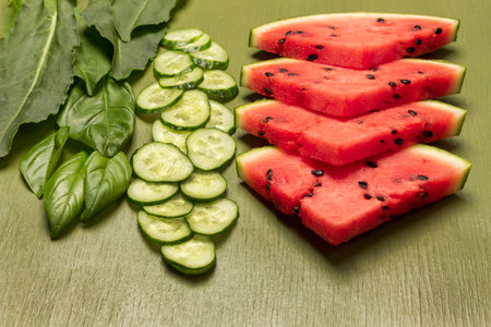 Chopped cucumber and basil leaves, pieces of watermelon. close up. green background. top viewの写真素材