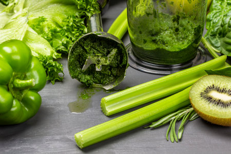 Making a vegetable smoothie. Blender and green vegetables on the table. close up. gray backgroundの写真素材