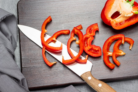 Kitchen knife, chopped red pepper, and half pepper on cutting board. flat lay. gray background.の写真素材
