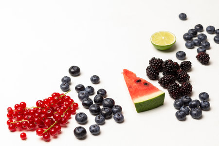 Ripe blackberries, blueberries, red currants and a slice of watermelon and half lime. copyspace. top view. white background.の写真素材