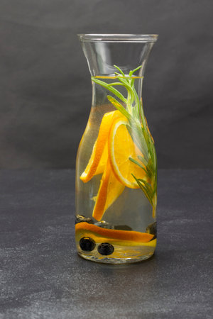 Infused summer drink with oranges, blueberries and rosemary. close up. copyspace. Black background.の写真素材