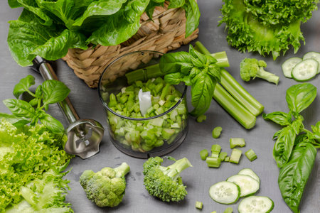 Chopped celery stalks in blender. Broccoli, cucumbers, lettuce on table. flat lay. gray background.の写真素材