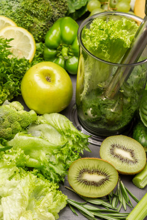 Kiwi, apple and lettuce on table. Green smoothie in blender bowl. gray background. top viewの写真素材