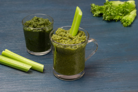 Green smoothie in glasses. Celery stalks on the table. copyspace. blue background.の写真素材