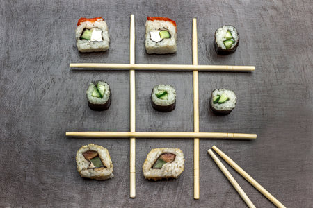 Chopsticks are laid out crosswise, sushi lies between the chopsticks. copyspace. flat lay. brown backgroundの写真素材