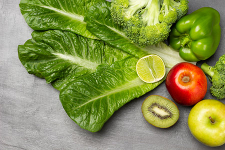 Lettuce, broccoli and peppers, kiwi and lemon halves, apples on table. flat lay. green background.の写真素材