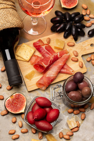 Aperitif set. Jamon and crackers on board. Bottle of red wine, glass of red wine, figs and nuts. flat lay. Rusty metal background.の写真素材
