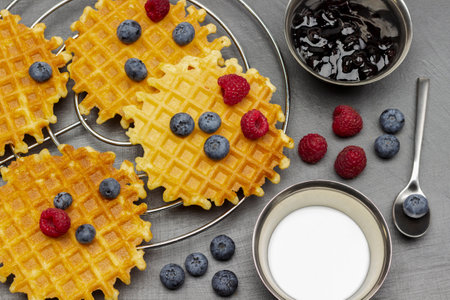 Berries and waffles. Cream and jam in metal bowls. Blueberries in spoon. flat lay. gray background.の写真素材