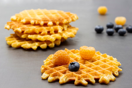 Yellow raspberries and blueberries on waffles. Berries and waffles on table. gray background.の写真素材