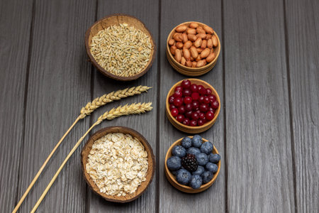 Ingredients for balanced breakfast. Oatmeal, cranberries and blueberries in wooden bowls. Sprigs of...