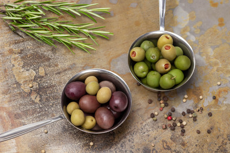 Olives of different varieties in a metal bowl. Rosemary and allspice. flat lay. Rusty metal background.の写真素材