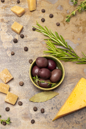 Olives in a bowl, a sprig of rosemary and pieces of cheese. flat lay. Rusty metal background.の写真素材