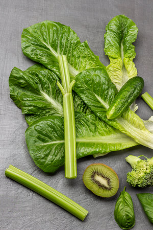 Set of green vegetables. Lettuce, celery stalks, half kiwi and cucumber. flat lay. gray background.の写真素材