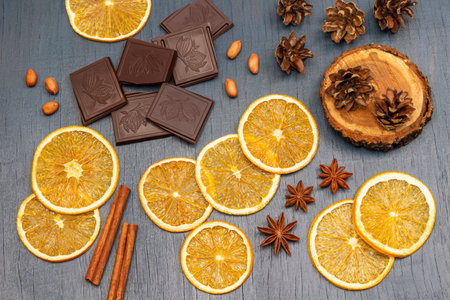 Slices of dry orange, pieces of chocolate, cinnamon sticks and cones on a stump. flat lay. gray background.の写真素材
