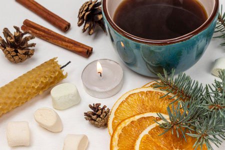 A mug of coffee, a lit candle, a spruce branch, cones and dry orange slices. top view. white background.の写真素材