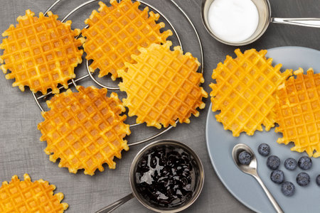 Waffles on the table and on the plate. Jam and cream in bowls. flat lay. gray background.の写真素材