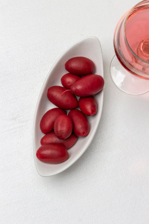 Red olives in a white bowl, a glass of red wine. white background. copyspace. flat lay.の写真素材
