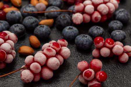 Frozen bunches of red berries and nuts. close up. Black background.の写真素材