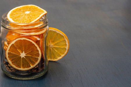 Dry orange slices and fir cones in glass jar. Christmas decorations. copyspace. top view. blue background.の写真素材