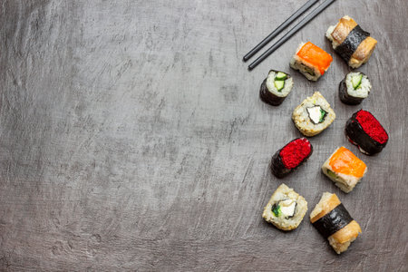 Sushi of different types. copyspace. flat lay. Black chopsticks. brown background.の写真素材