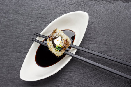 Sushi on chopsticks and on a white plate with sauce. flat lay. Black background.の写真素材