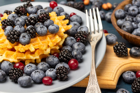 Berries, waffles and a fork on a gray plate. Berries on the table. gray background. close up.の写真素材
