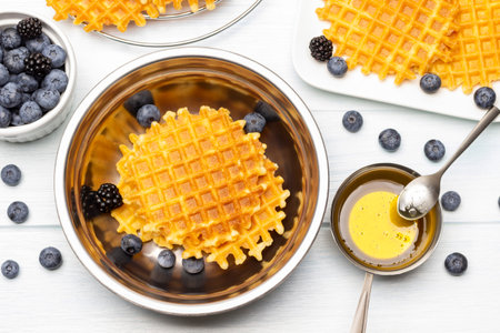 Viennese waffles and berries in a metal bowl. Honey in a bowl. Blueberries on the table. flat lay. white background.の写真素材