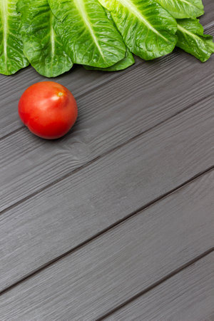 Tomato and lettuce leaves on a dark wooden background. copyspace. flat layの写真素材