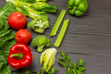 Red peppers and tomatoes, celery and broccoli and lettuce. copyspace. Dark wooden background.の写真素材