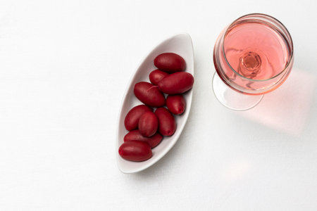 Glass of rose wine and olives in a white plate. copyspace. flat lay. white background.の写真素材