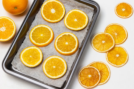 Dry orange slices on table. Fresh orange slices on baking tray. flat lay. white background.の写真素材