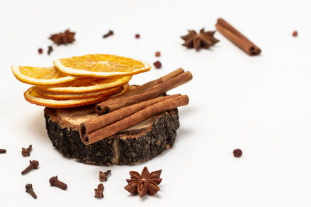 Cinnamon sticks and dry orange chips on hemp. Star anise and cloves on the table. copy space. white background.の写真素材